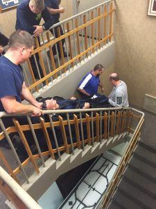 Group Carrying a Dummy down the Stairs